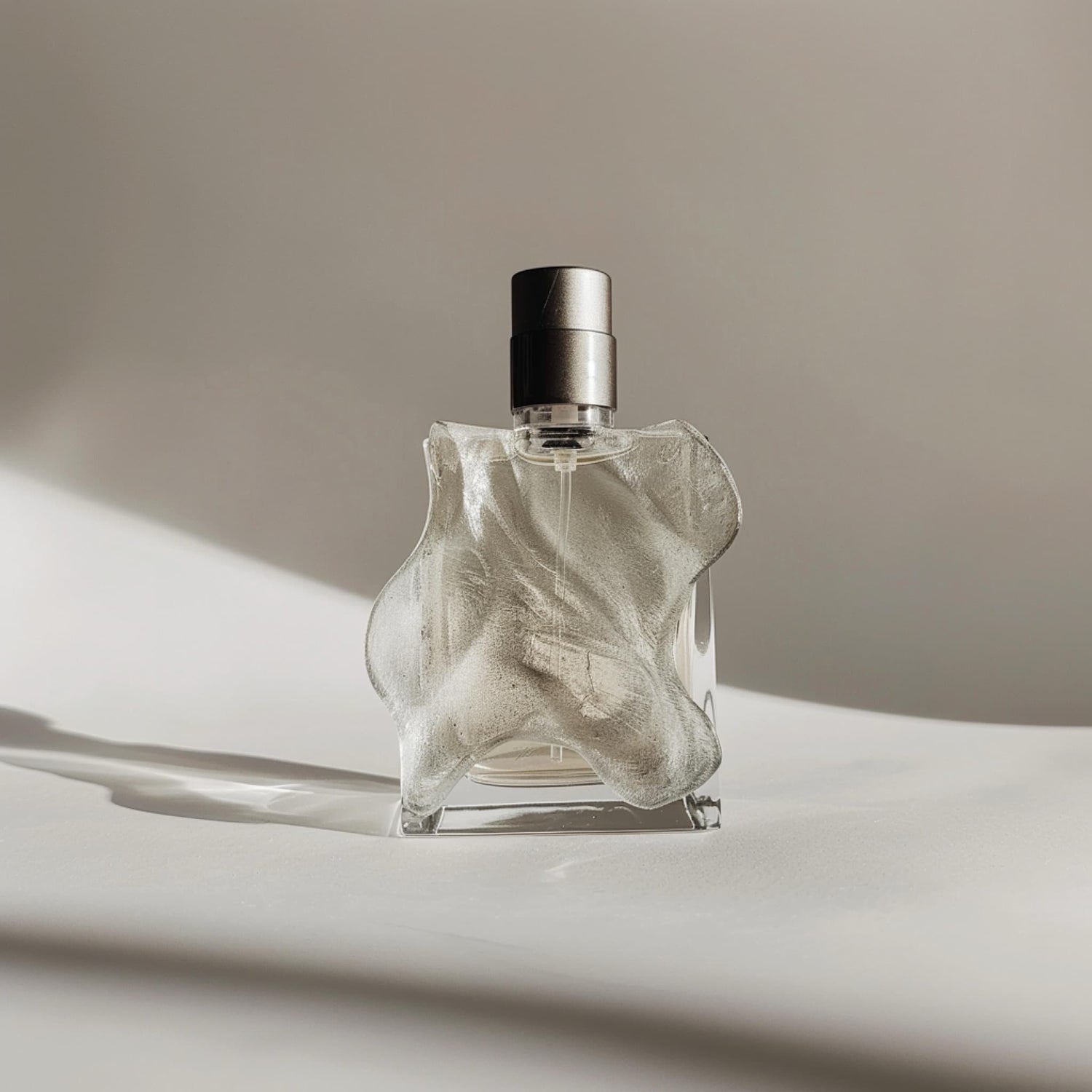 Elegant OKAISON glass perfume bottle with turquoise liquid and cap, placed on a desk beside a watch and leather accessory.